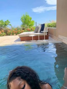 a woman laying in the water next to a swimming pool