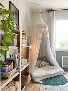 a bedroom with a hammock bed, bookshelf and plants in it