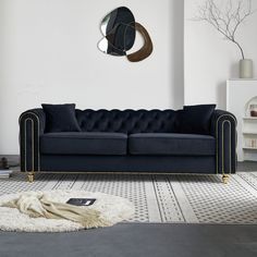 a living room with a black couch and white rug in front of a mirror on the wall