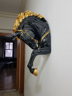 a black and gold horse head mounted to the side of a white wall next to a doorway