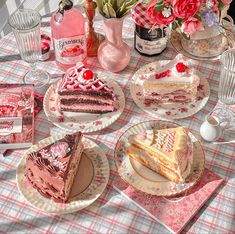 there are many pieces of cake on the table with pink flowers in the vases