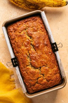 a loaf of banana bread sitting on top of a counter next to two ripe bananas