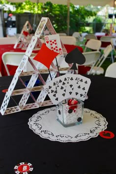 a black table topped with white and red tables cloths covered in cards, playing cards on top of each other