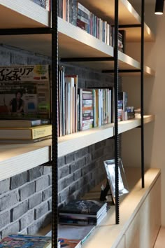 a bookshelf filled with lots of books next to a brick wall