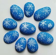 blue and white painted rocks with snowflakes arranged in a circle on a white surface