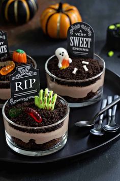 three desserts decorated with halloween decorations on a black plate