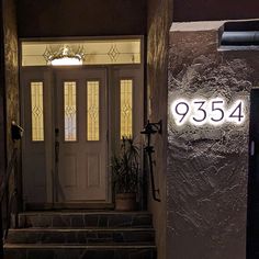 a house number sign on the front door of a home at night with light coming through