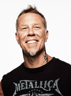 a man with tattoos on his neck and chest smiles at the camera while wearing a black shirt