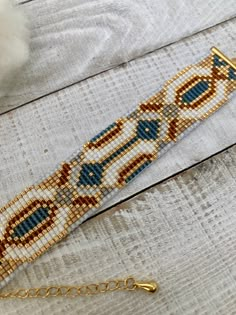 the beaded bracelet is sitting on top of a table next to a white fluffy ball