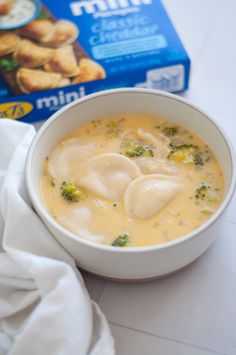 a bowl of broccoli and cheese soup next to a box of frozen milk