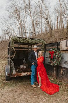 a man and woman standing in front of an old truck with wreaths on it