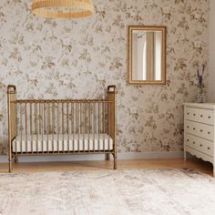 a baby's crib and dresser in a room with floral wallpaper on the walls