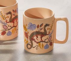 two mugs with designs on them sitting next to each other