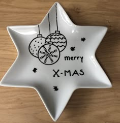 a white ceramic star ornament with ornaments on it that says merry x - mas