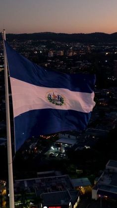 the flag of el salvador is flying high in the sky at night with city lights behind it