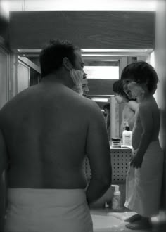 a man and woman standing in front of a bathroom mirror with their backs turned to the camera