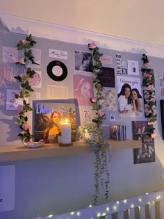 there is a wall with many pictures on it and candles in front of the bookshelf