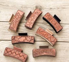 several different types of leather knives on a wooden table