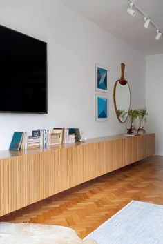 a television mounted on the wall in a living room with wood floors and white walls