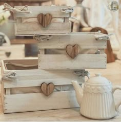 three wooden crates with hearts on them and a teapot next to one that is sitting on a table