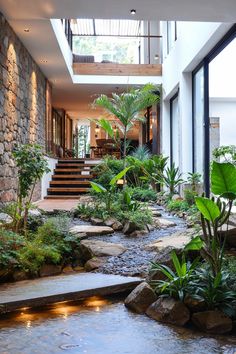 the inside of a house with plants and water in it's courtyard area, along with stairs leading up to the second floor