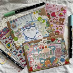 various stationery items laid out on a bed with markers, pens and notebooks