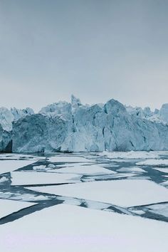 an iceberg is seen in the distance with snow and ice floes around it