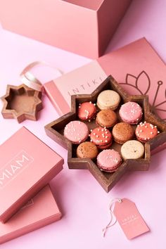 a pink box filled with assorted cookies on top of a table