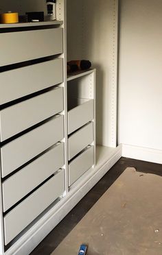 a cell phone is laying on the floor in front of a white cabinet with drawers