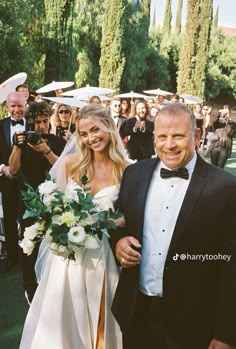 a bride and groom walking down the aisle at their outdoor wedding ceremony with guests in the background