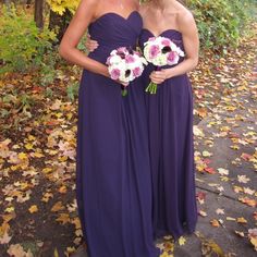 two women in purple dresses standing next to each other with bouquets on their heads