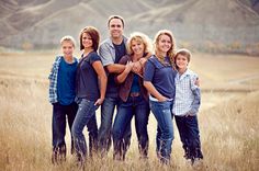 a family posing for a photo in a field with mountains in the background at sunset