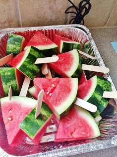 watermelon slices and toothpicks are arranged on a foil tray in the kitchen