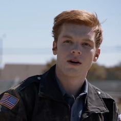 a young man with red hair and an american flag on his jacket