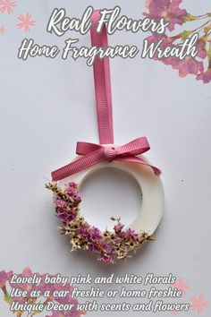 a white wreath with pink flowers hanging from it's side and the words real flowers home fragrance wreath