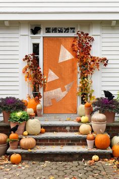 pumpkins and gourds are sitting on the steps outside of a house with an orange door