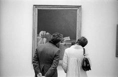 black and white photograph of two people looking at an art work on display in a museum