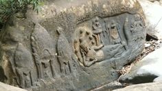 an ancient rock carving with people and animals on it's sides in the jungle