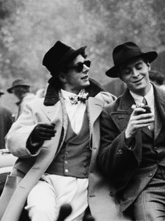 two men in suits and hats are looking at their cell phones