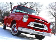 an old red truck is parked in the snow