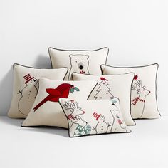 four pillows with white and red designs on them, one in the shape of a polar bear