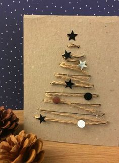 a christmas tree made out of driftwood and stars on the front is displayed next to a pine cone