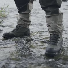 a person standing in the water wearing hiking boots