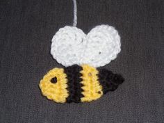 a small crocheted bee ornament hanging from a string on a gray surface