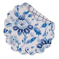 a blue and white flowered dish on a white tablecloth with an embroidered edge