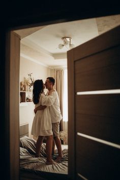 a man and woman standing on top of a bed in a bedroom next to each other