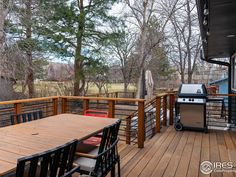 an outdoor grill and table on a deck with trees in the backgrouund