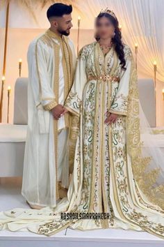 two people standing next to each other wearing white and gold outfits