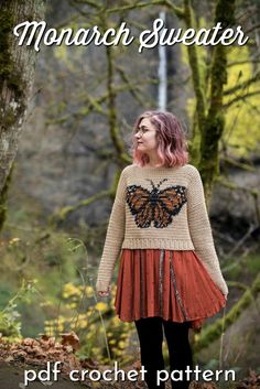 a woman standing in the woods wearing a sweater with a butterfly on it's back