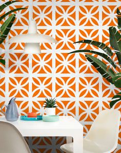 an orange and white wallpaper with geometric design in the dining room, next to two chairs